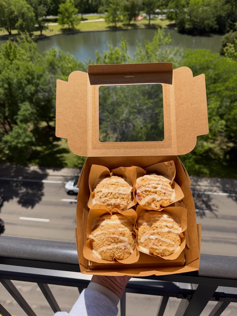 A kraft box of streusel muffins held up in the sun.