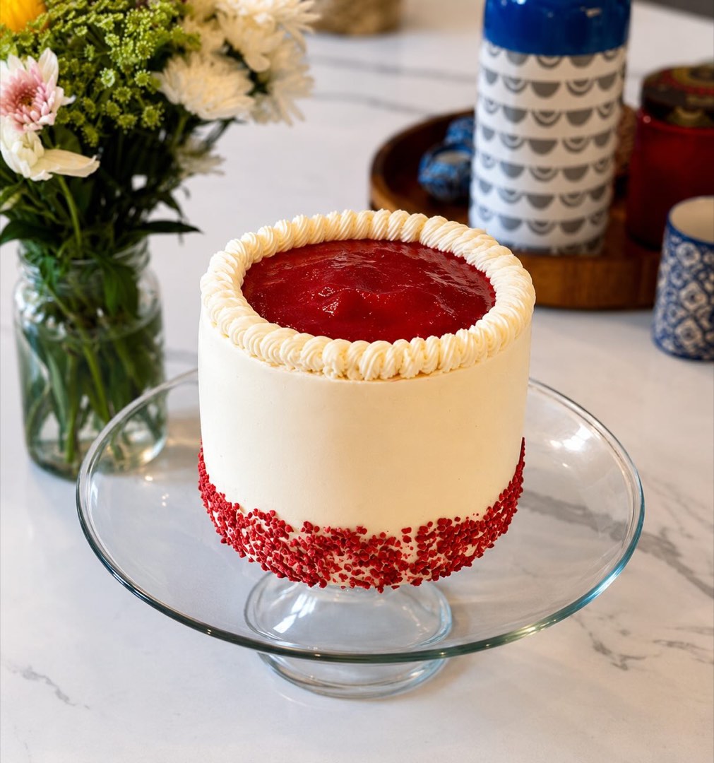A buttercream cake with a glossy strawberry-glazed top.